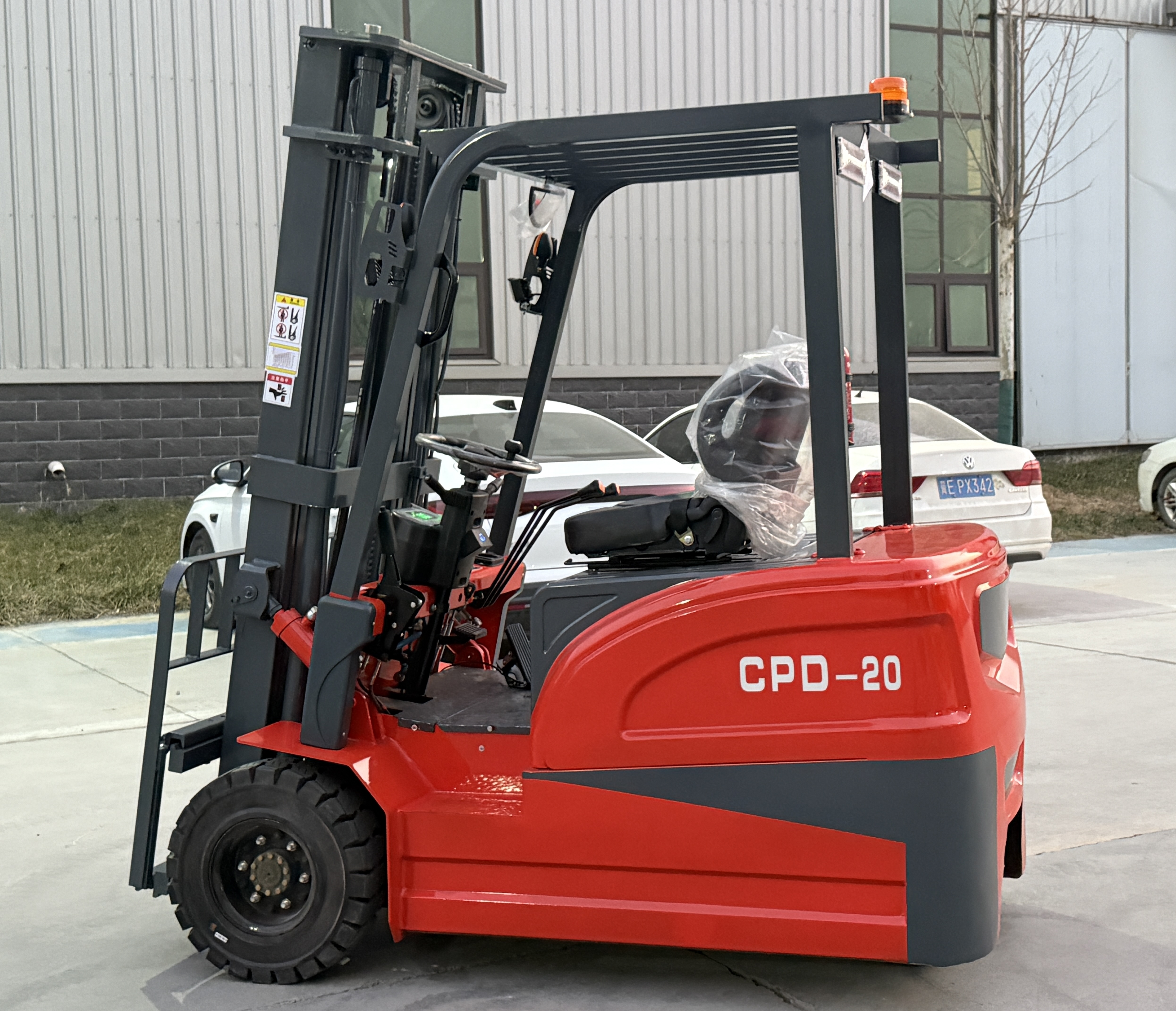 Gangchi 2 ton three wheel electric forklift with mast raised inside a warehouse aisle